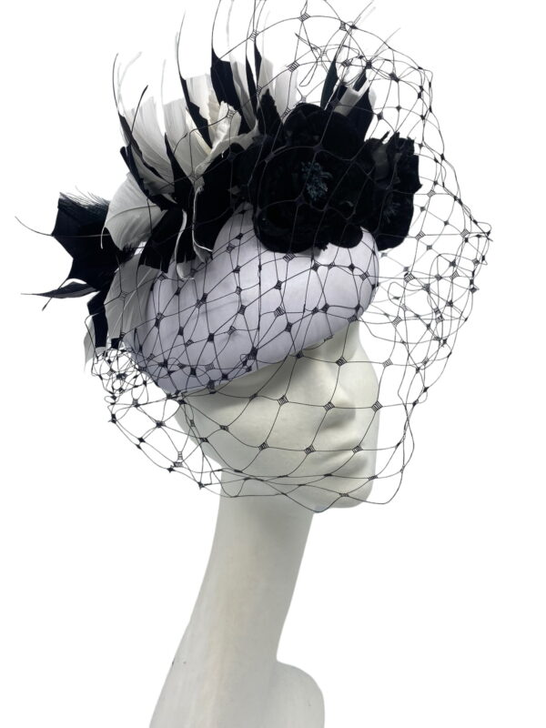 Stunning light grey leather based headpiece with stunning black face veiling and dramatic black feather detail. 